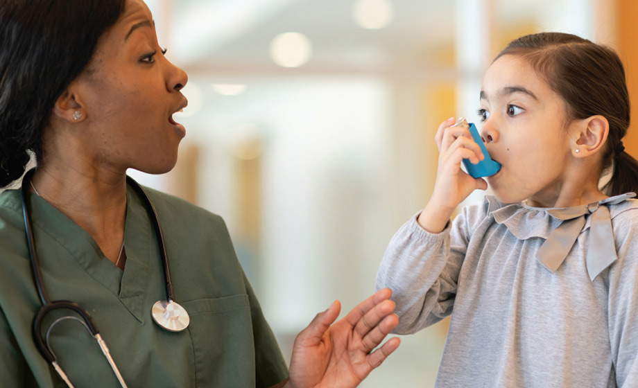 Healthcare worker teaching little girl how to use inhaler